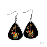 Close-up of handcrafted Stella’s Flight earrings showing vibrant butterfly-and-guitar artwork under a glossy epoxy finish.