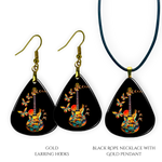 Close-up of handcrafted Stella’s Flight earrings and necklace pendant set showing vibrant Golden Road Festival butterfly-and-guitar artwork under a glossy epoxy finish.