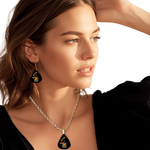 Stella’s Flight necklace featuring glossy black background and the Golden Road Festival guitar and butterfly design.