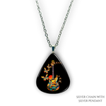 Close-up of handcrafted GRF Stella’s Flight necklace showing the vibrant Golden Road Festival butterfly-and-guitar artwork under a glossy epoxy finish.