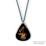 Close-up of handcrafted GRF Stella’s Flight necklace showing the vibrant Golden Road Festival butterfly-and-guitar artwork under a glossy epoxy finish.