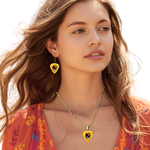 GRF – Golden Road Flight jewelry set on model featuring yellow glossy guitar pick design with the golden road festival bird and Steal Your Face logo.